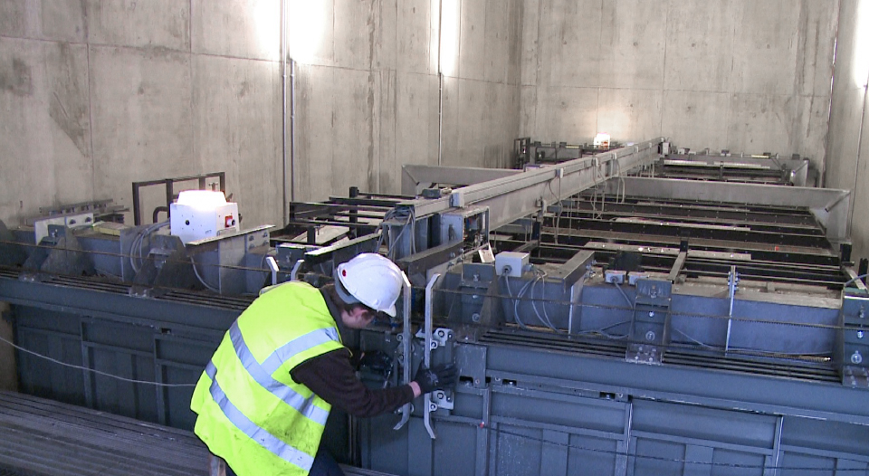 Engineer repairing vehicle lift with PPE